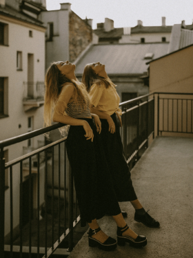 Two girls on a balcony looking at the sun with their heads tilted back